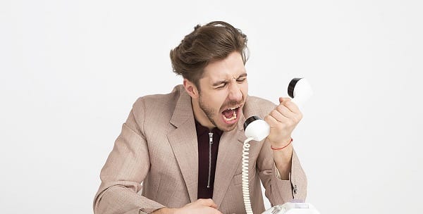 angry businessman screaming into a landline phone