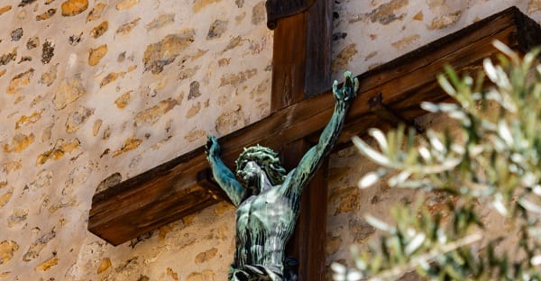 a crucifix affixed to the outside of a church wall in france