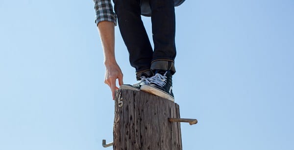 man balancing on top of telephone pole