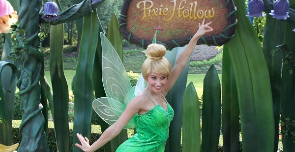 tinker bell posing in front of a sign reading "Pixie Hollow"