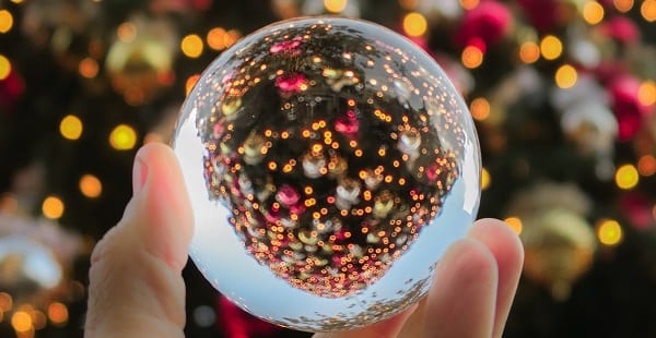 a multifaceted bauble in front of a lit christmas tree
