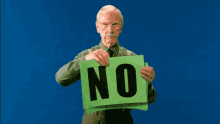 An old man holding up a bright green sign saying "NO"